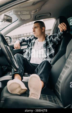 Young man relaxed sitting in car thoughtful mood Stock Photo