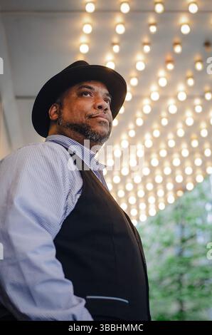 A dark-skinned man in a hat against a backdrop of glowing lamps Stock Photo