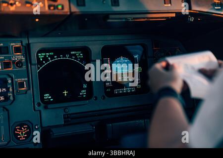 Aircraft navigation screens and pilot with checklist in cockpit Stock Photo