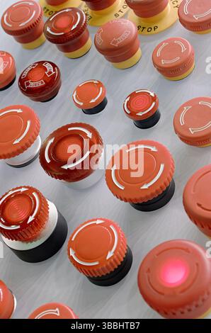 Multiple red emergency stop buttons on a grey metal panel, close up ...