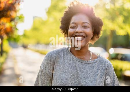 Smiling young woman in the park on a sunny day Stock Photo