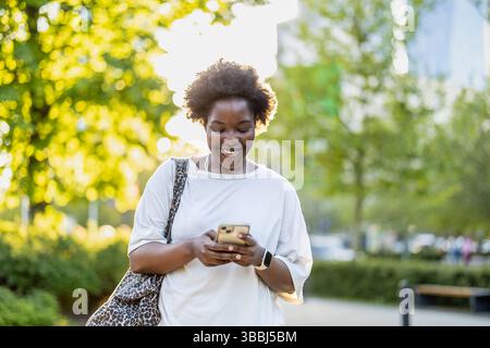 Smiling young woman using mobile phone in the city Stock Photo