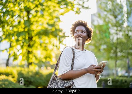 Smiling young woman using mobile phone in the city Stock Photo