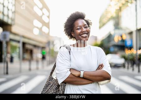 Portrait of a smiling young woman standing in the city on a sunny day Stock Photo
