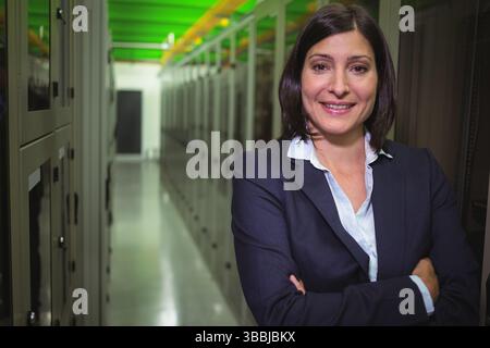 Server racks are lining modern data center aisle, featuring green and orange cable trays Stock Photo