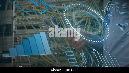 Grasping hand connecting Ethernet cables to patch panel ports at data center, with digital overlays Stock Photo