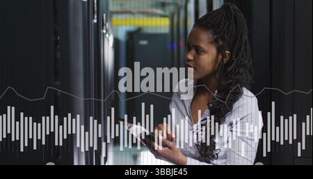 Image of graphs and data over african american woman in server room Stock Photo