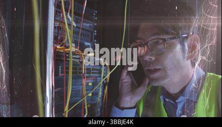 Image of lights over asian man with smartphone working in server room Stock Photo
