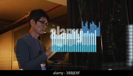 Image of data processing against asian male engineer working in computer server room Stock Photo