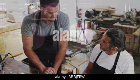 Image of financial graphs over caucasian men working in carpentry workshop Stock Photo