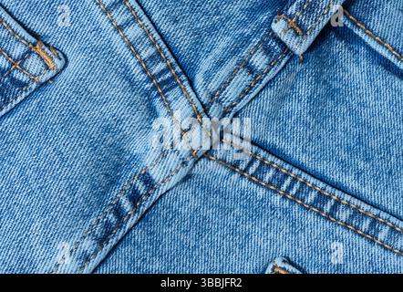 Close-up of blue denim jeans fabric showing reinforced cross-stitching. Detailed view of the seam and textile texture for design and quality themes Stock Photo