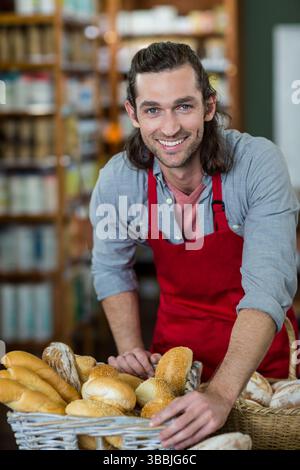Smiling man leaning on counter in small bakery, with wicker baskets of fresh bread Stock Photo