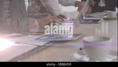 Image of lights and graphs over hands of diverse businesspeople working on laptops Stock Photo