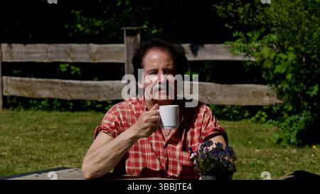 Attractive man holding a cup of coffee in a park in the sun. Stock Photo