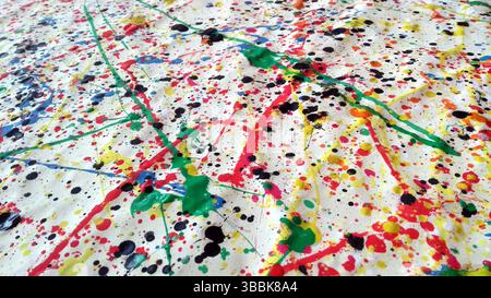 Close-up of vibrant abstract splatter painting with black, red, yellow, green, and blue ink on crumpled white paper, evoking energy and artistic spont Stock Photo