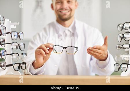 Young happy optician doctor holding eyeglasses in hands working in medical clinic Stock Photo