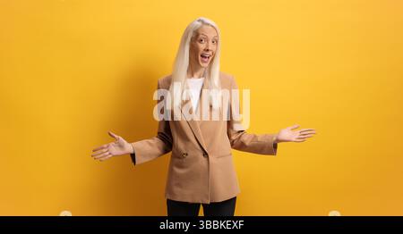 Excited professional woman posing against yellow background Stock Photo