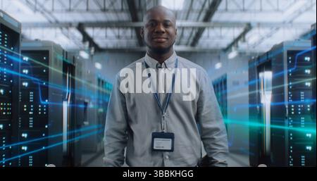 African American Administrator with Digital Tablet Walking in Futuristic Big Data Center with VFX, Looking at Camera. Animated Diagrams of Internet Traffic on Servers. Information Digitalization. Stock Photo