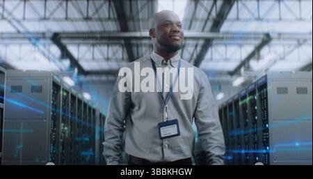 African American Administrator with Digital Tablet Walking in Futuristic Big Data Center with VFX, Looking at Camera. Animated Diagrams of Internet Traffic on Servers. Information Digitalization. Stock Photo