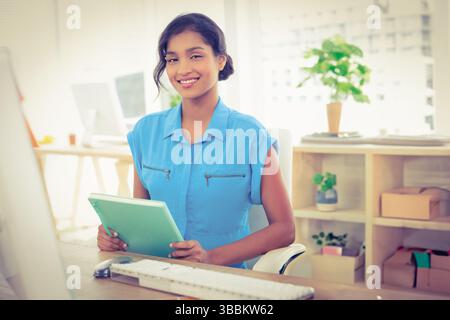 Green tablet resting on wooden desk in modern office, featuring keyboard mouse and plants Stock Photo