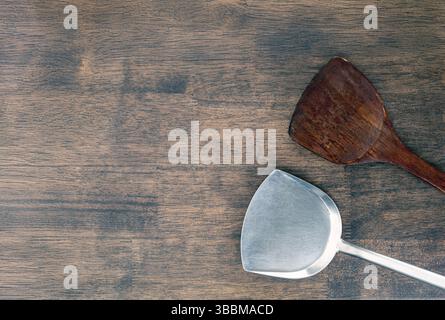 A wooden and metal spatulas on rustic wooden table, showcasing blend of natural and industrial materials. contrast highlights versatility and function Stock Photo