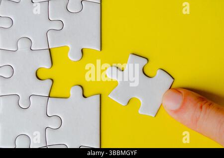 Hand fitting a missing white jigsaw pieces. Stock Photo