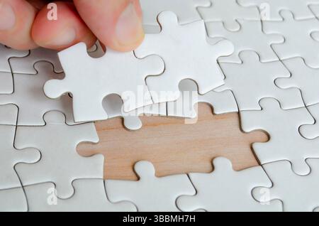 Hand placing missing jigsaw puzzle pieces. Solution concept. Stock Photo