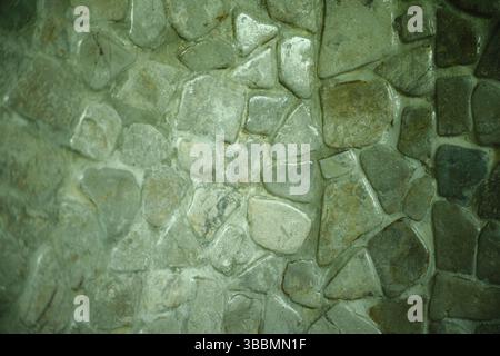 A close-up image of a textured stone wall made of irregularly shaped rocks Stock Photo