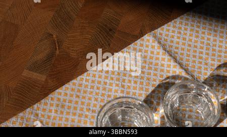 Two Vodka Shots on Wooden Table with Napkin in Sunlight Stock Photo
