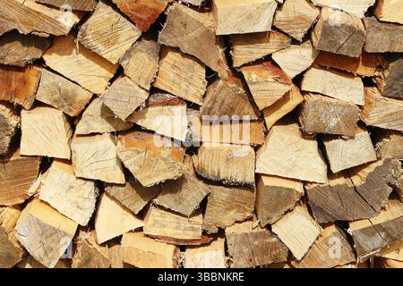 Stack of chopped firewood. Natural wooden logs for winter. Cut timber pieces background. Rustic fuel resource. Dry fire woodpile texture. Forest pile. Stock Photo