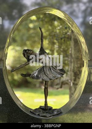 A delicate bronze ballerina poised mid-dance, captured within a circular frame Stock Photo
