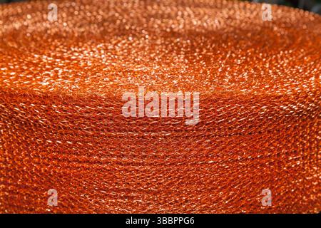 The texture of a soft copper mesh twisted into a roll. Stock Photo