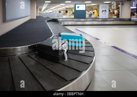 Airport baggage system transfers suitcases from plane to terminal conveyor belt. Travel bags wait Stock Photo