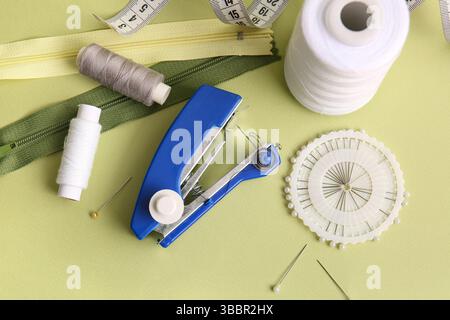 Manual sewing machine with different supplies on green background Stock Photo