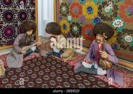 Traditional folk musicians in colorful costumes perform on patterned carpets in Khiva Uzbekistan surrounded by vibrant textile art. Stock Photo