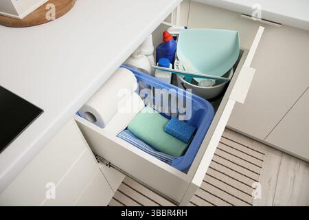 Drawer with cleaning supplies, paper towels and baskets in modern kitchen Stock Photo