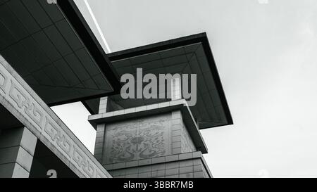 A modern Chinese-style building photographed from a low angle, showcasing overhanging eaves, geometric lines, and traditional decorative patterns Stock Photo