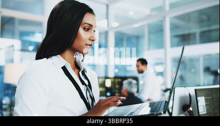 Woman, developer and reading on laptop in office of programming, coding support and server update. Person, online app and IT for testing system Stock Photo