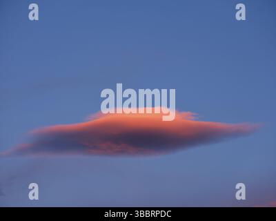Red-coloured lenticularis cloud in the blue evening sky Stock Photo