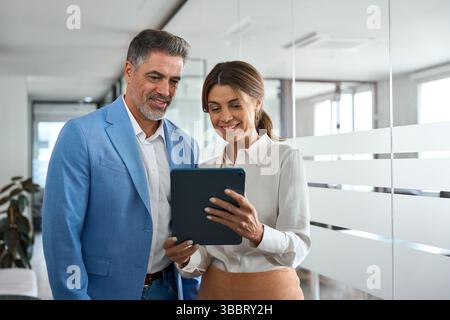 Two happy business executives team people using digital tablet in office. Stock Photo