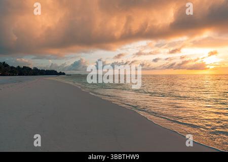 Peaceful sunset tropical beach landscape calm sea and vivid reflections under colorful sky creating a serene summer vacation and travel destination Stock Photo