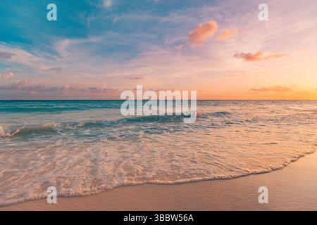 Serene views. Gorgeous sunset beach with calm waves and colorful sky, soft clouds over tranquil ocean seascape, peaceful tropical evening nature scene Stock Photo