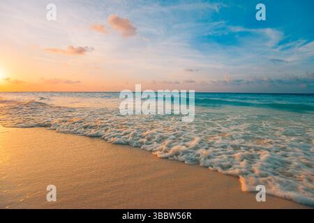 Serene views. Gorgeous sunset beach with calm waves and colorful sky, soft clouds over tranquil ocean seascape, peaceful tropical evening nature scene Stock Photo
