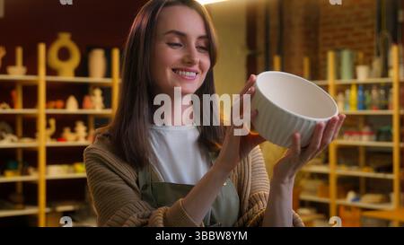 Happy Caucasian woman artist female potter small business owner saleswoman decorator sculptor clay modeling crock designer girl holding ceramics bowl Stock Photo