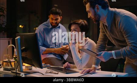 Multiracial team business colleagues Caucasian Indian men woman businessmen businesswoman cooperate work in night office diverse co-workers discuss Stock Photo
