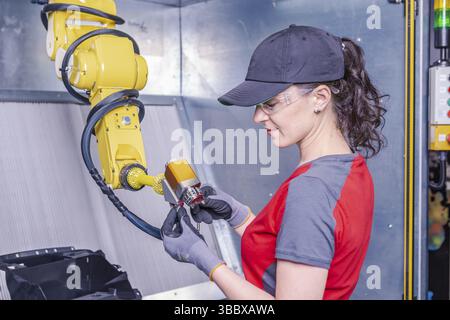 A young female technician while machine constructing in a manufacturing plant Stock Photo