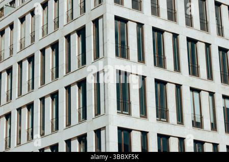 A modern urban architectural view of a building's facade featuring many identical rectangular windows and balconies, showcasing a minimalist design. Stock Photo