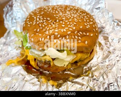 A cheeseburger on it's foil wrapper in a fast food restaurant Stock Photo