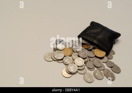 grouping of coins spilling out of a black leather pouch Stock Photo