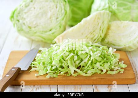 Whole and sliced fresh green cabbage on a white wooden table. Stock Photo